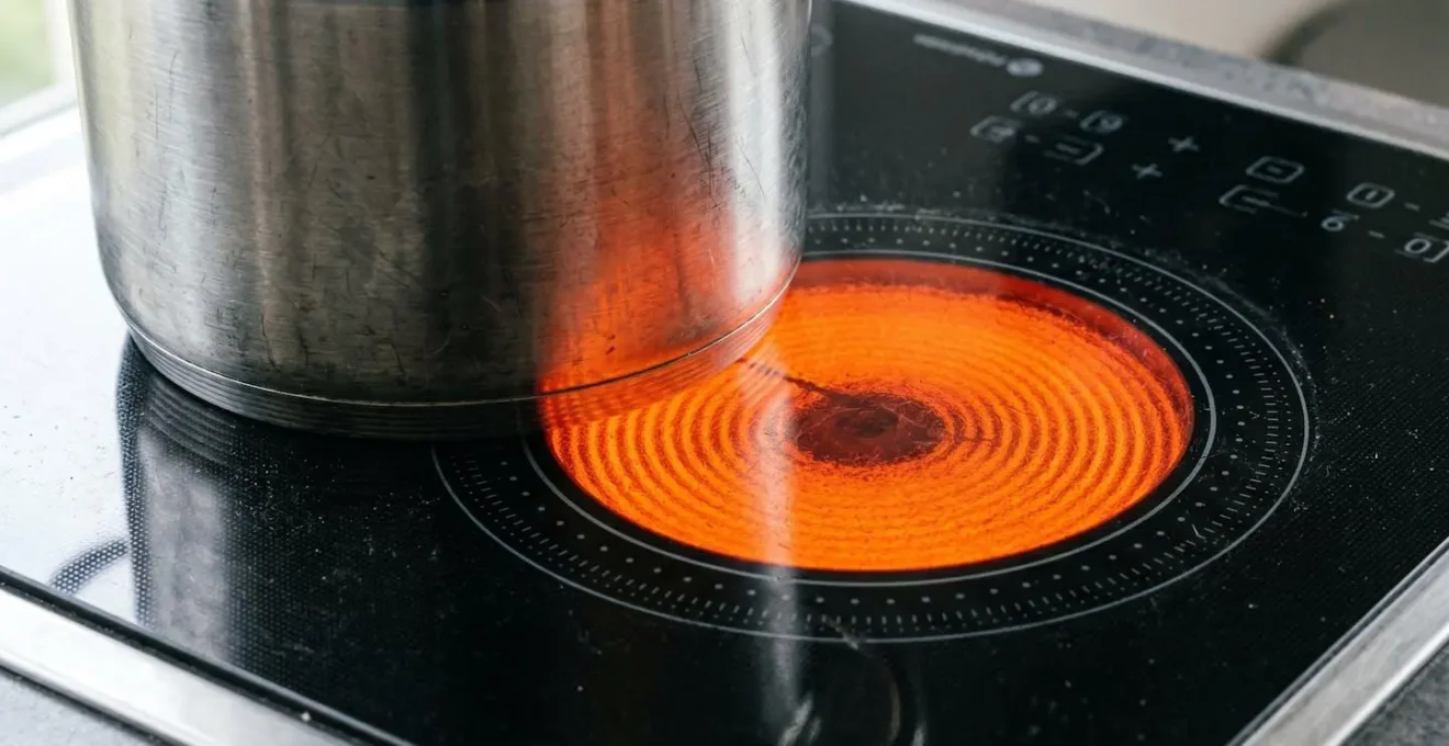 Gros plan sur une surface de plaque à induction noire avec zone de cuisson activée et casserole en acier inoxydable